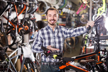 man checks bicycle handlebar in shop when choosing bike