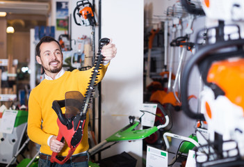 Guy deciding on best hedge cutter