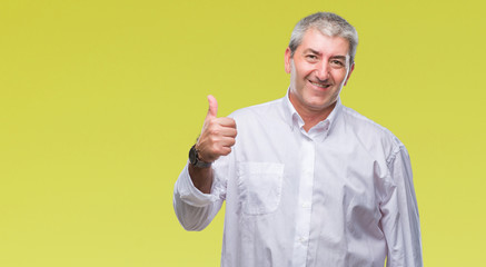 Naklejka premium Handsome senior man over isolated background doing happy thumbs up gesture with hand. Approving expression looking at the camera with showing success.