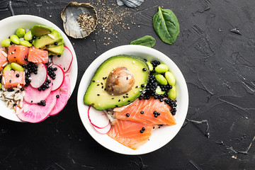 Fresh seafood recipe. Salmon gravlax poke bowl with fresh prawn, brown rice, cucumber, pickled sweet onion, radish, soy beans edamame portioned with black and white sesame. Food concept poke bowl