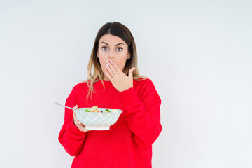 Young woman eating fresh healthy salad over isolated background cover mouth with hand shocked with shame for mistake, expression of fear, scared in silence, secret concept