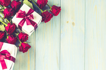 Red roses and gift box on light blue wooden table, top viewed
