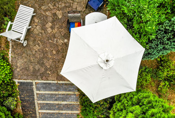 Vertical aerial photograph of a bright parasol on a terrace, taken from close up with the drone. © Frank