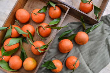 Fresh mandarin oranges fruit or tangerines with leaves on the wooden box on the table. 