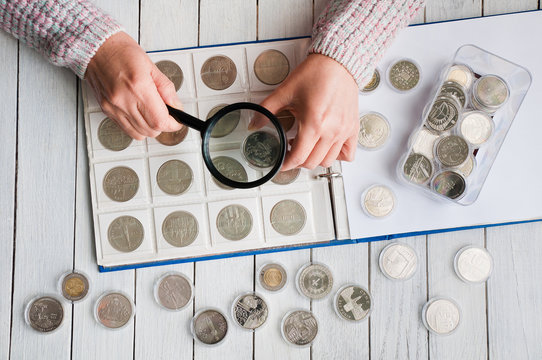 Man numismatist examines coin with magnifying glass Stock Photo by