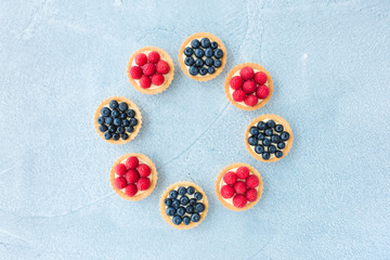 Raspberry and Blueberry Tartlets on Blue Concrete Background
