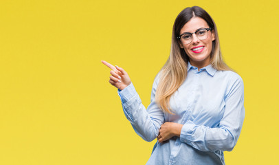 Young beautiful business woman wearing glasses over isolated background with a big smile on face, pointing with hand and finger to the side looking at the camera.