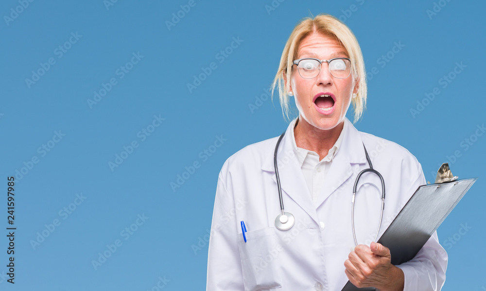 Sticker Middle age blonde doctor woman holding clipboard over isolated background scared in shock with a surprise face, afraid and excited with fear expression