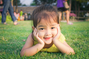 happy little girl lying on green grass and playing in the park. soft focus.