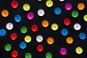 Fototapeta premium Black textured background with colorful buttons, fashion backdrop
