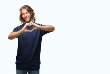 Young handsome man with long hair wearing winter sweater over isolated background smiling in love showing heart symbol and shape with hands. Romantic concept.