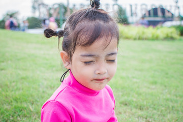 happy little girl sitting on green grass and playing in the park. soft focus.