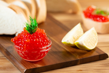 red caviar in glassware on a wooden background in a rustic style with space for text