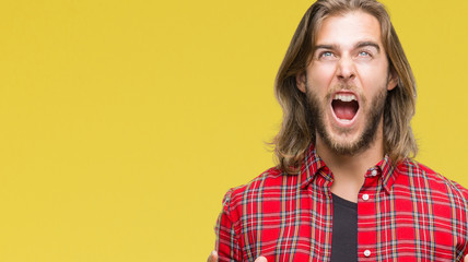 Young handsome man with long hair over isolated background crazy and mad shouting and yelling with aggressive expression and arms raised. Frustration concept.