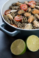 Fototapeta na wymiar Fusilli made of hemp flour and served with tomatoes and mussels, close-up, vertical shot