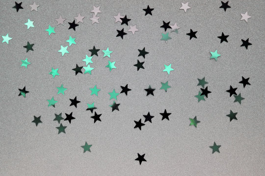 Star-shaped Confetti Sprinkled on a Silver Brocade Background. Black, Turquoise and Silver Glowing Stars. Funny Party Layout. Carnival Composition.