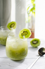 A glass of freshly squeezed kiwi juice is on a wooden table