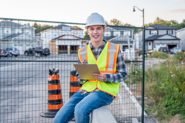 Fototapeta na wymiar Happy young construction worker wearing safety gear and holding a clipboard.