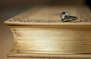 Metal nickel-plated detail of a vintage camera lying on old book with a gold edge