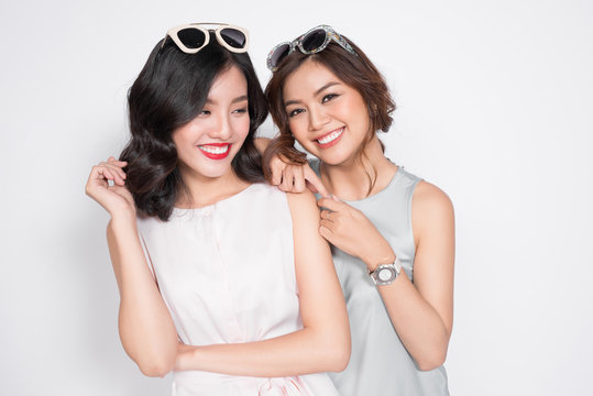 Image of a happy young two girls friends posing isolated over white wall dressed