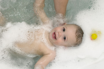 Kid, baby boy taking bath, having fun in foam