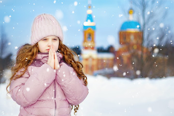Little girl prays in front of the church. © ulkas