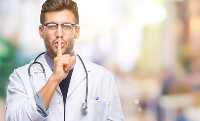 Young handsome doctor man over isolated background asking to be quiet with finger on lips. Silence...