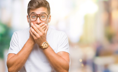 Young handsome man wearing glasses over isolated background shocked covering mouth with hands for mistake. Secret concept.