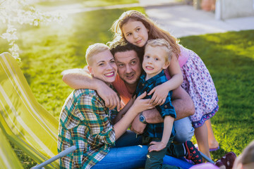 Picture of happy family in park hugging and looking at the camera with big smile on his face.