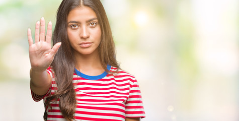 Young beautiful arab woman over isolated background doing stop sing with palm of the hand. Warning expression with negative and serious gesture on the face.