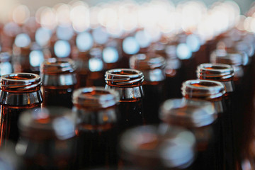 The necks of empty glass bottles of brown color, standing in a box. Empty containers for beer,...