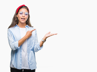 Young beautiful arab woman wearing sunglasses over isolated background amazed and smiling to the camera while presenting with hand and pointing with finger.