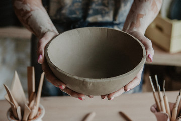 Pottery, clay, ceramics art concept - closeup on hands of young master with the large plate from fireclay