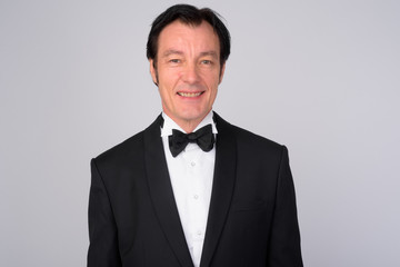 Happy mature handsome businessman smiling and wearing tuxedo