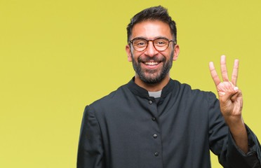 Adult hispanic catholic priest man over isolated background showing and pointing up with fingers number three while smiling confident and happy.