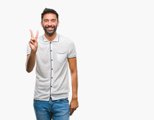 Fototapeta premium Adult hispanic man over isolated background smiling with happy face winking at the camera doing victory sign. Number two.