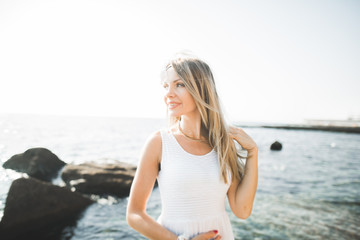 portrait of young woman posing near sea, wearing a dress