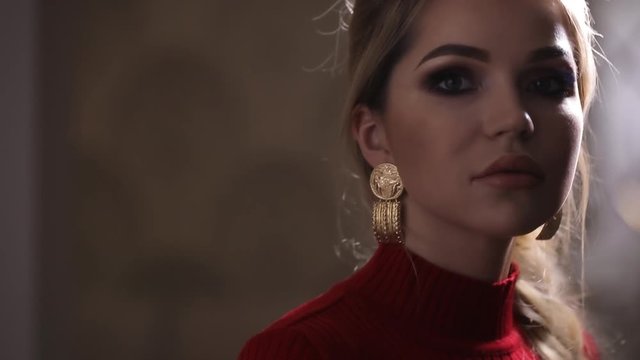 Beautiful fashion model in red dress posing with earrings