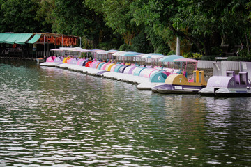 Fototapeta premium Colorful pedal Rental Boats in the public parked on the lake at Khao Din Zoo in Thailand. Water bike pedal boat, Row of spinning boats.