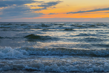 Low waves on Baltic sea at sunset. Cosy flat sandy beach.