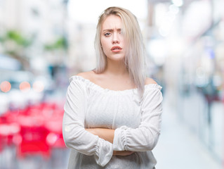 Young blonde woman over isolated background skeptic and nervous, disapproving expression on face with crossed arms. Negative person.