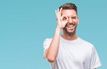 Fototapeta premium Young handsome man over isolated background doing ok gesture with hand smiling, eye looking through fingers with happy face.