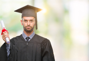 Young handsome graduated man holding degree over isolated background with a confident expression on smart face thinking serious