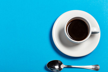 Tazza di caffè con cucchiaino su sfondo azzurro
