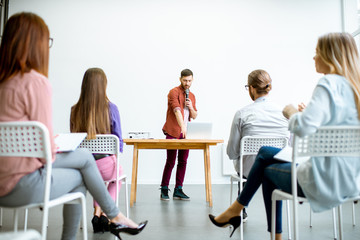 Young male speaker reporting to the audience during the meeting in the conference room with charts...