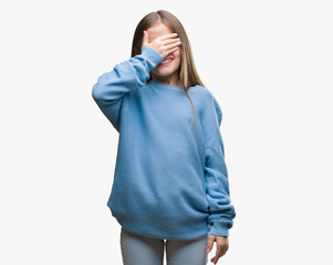 Young beautiful girl wearing winter sweater over isolated background smiling and laughing with hand on face covering eyes for surprise. Blind concept.