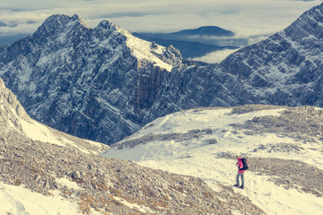 Female alpinist descending into mountain valley crossing flakes of snow.