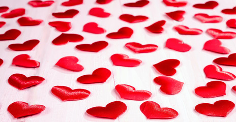 Red bright hearts on a light pink background. Selective focus.