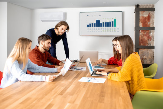Coworkers dressed casually sitting together during the meeting in the boardroom with some charts and statistics