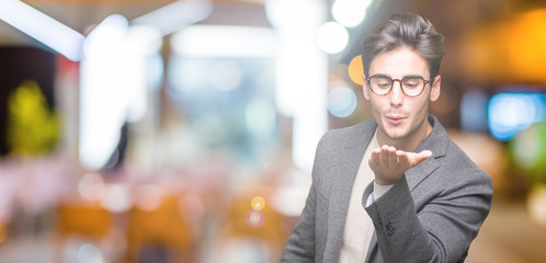 Young business man wearing glasses over isolated background looking at the camera blowing a kiss...